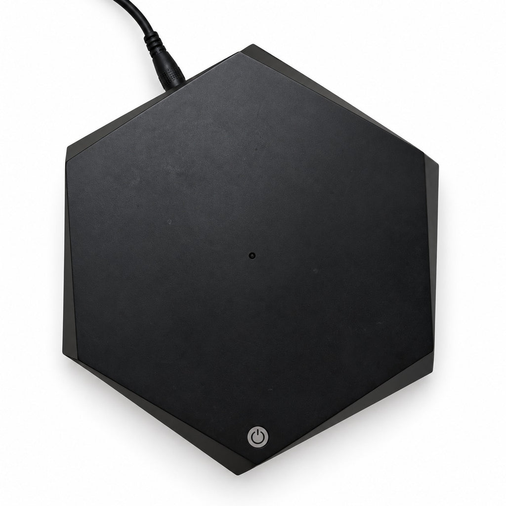Black hexagonal base seen from above, power button and plugged-in cable